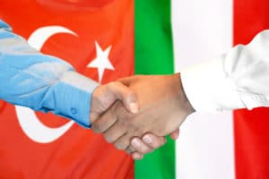 handshake on turkey and italy flag background.